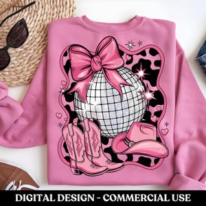 May include: Pink sweatshirt featuring a disco ball, cowboy hat, boots, and a pink bow on a black and white animal print background.