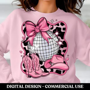 May include: Pink sweatshirt with a design featuring a disco ball, a pink bow, cowboy boots, and a cowboy hat. The design is on a black and white cow print background.