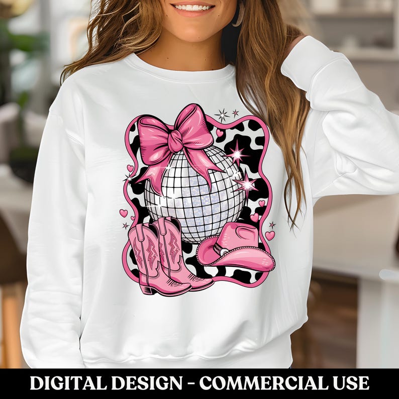 May include: White sweatshirt with a pink and white design featuring a disco ball, cowboy boots, and a cowboy hat. The design is set against a cow print background.
