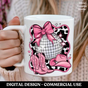May include: White ceramic mug with a pink and white design featuring a disco ball, cowboy hat, and cowboy boots on a black and white cow print background. The design includes a pink bow and stars.