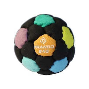 May include: A spherical footbag constructed from multiple pentagonal panels in black, teal, light blue, lavender, and yellow. A central orange panel features the white text FRANDO BAG with a logo above it. The surface has a soft, matte texture.