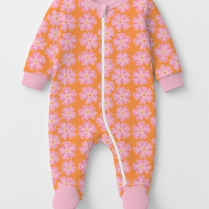 May include: A long-sleeve footed sleeper with a zipper closure, featuring an orange background with a repeating pattern of pink flowers with yellow centers. The garment has solid light pink ribbed trim at the neckline and sleeve cuffs.