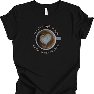Op de afbeelding: Zwart T-shirt met een witte afbeelding van een koffiekopje met de tekst "It's the simple things. Coffee is one of them."