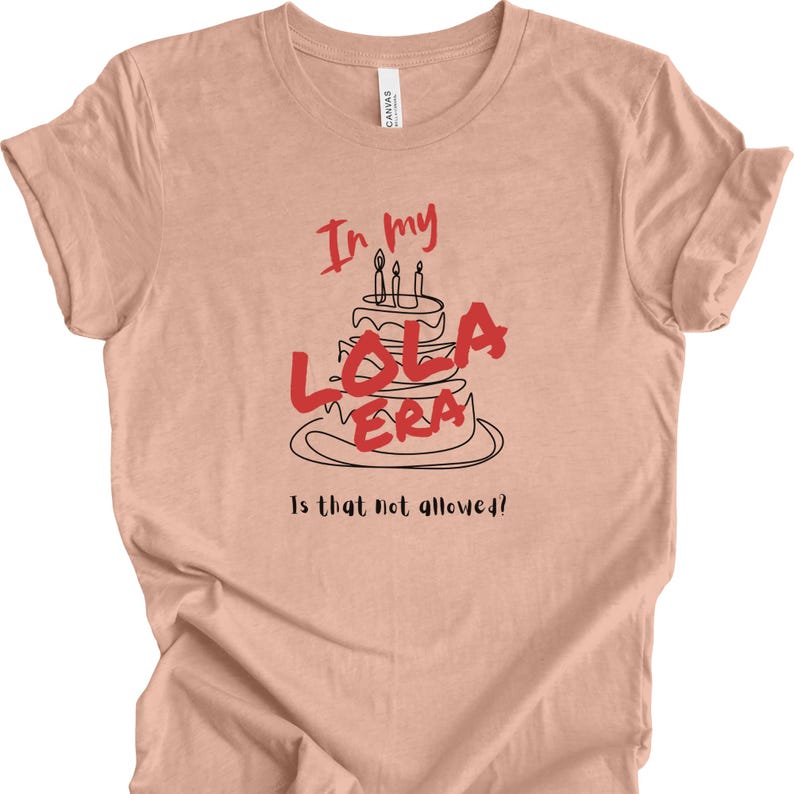 May include: A peach-colored t-shirt with a black and red graphic of a birthday cake with the text "In my Lola Era" and "Is that not allowed?!"