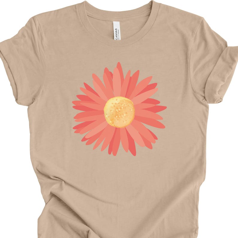 Puede incluir: Una camiseta beige con un estampado gr&aacute;fico de margarita rosa.