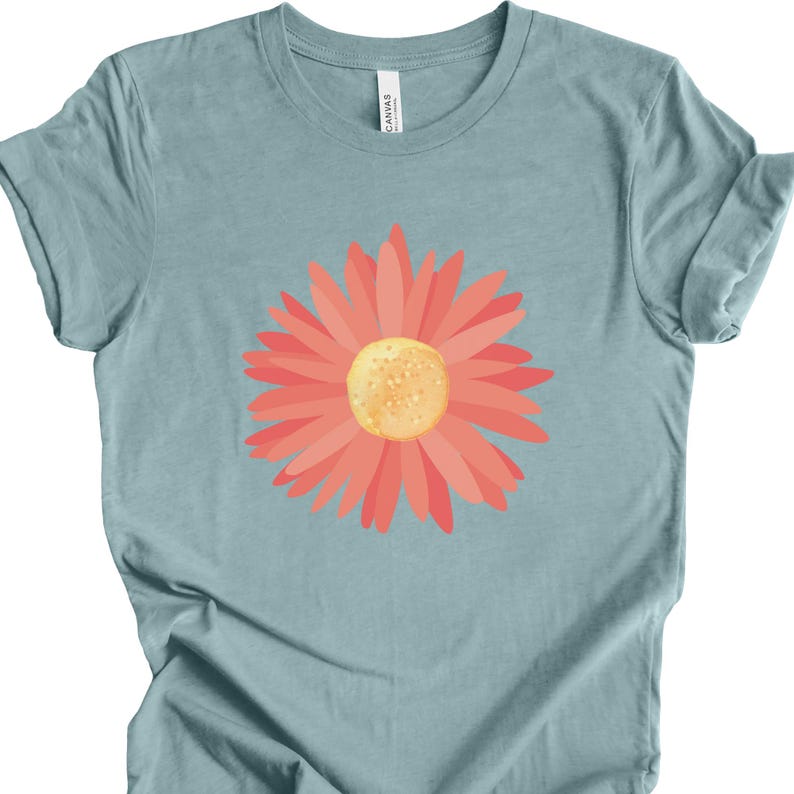 Puede incluir: Una camiseta azul claro con un gr&aacute;fico de margarita rosa.