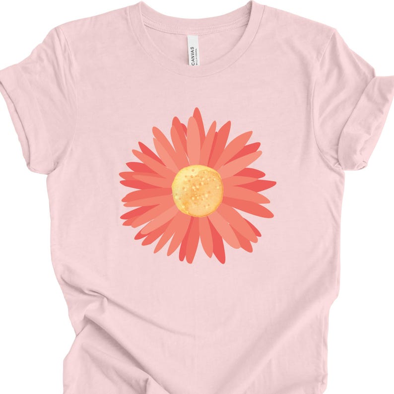 Puede incluir: Una camiseta rosa con un gr&aacute;fico de margarita de color coral.