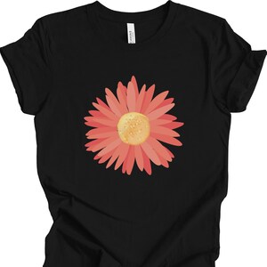 Puede incluir: Una camiseta negra con un gr&aacute;fico de flor rosa. La flor tiene un centro amarillo y est&aacute; en el centro de la camiseta.