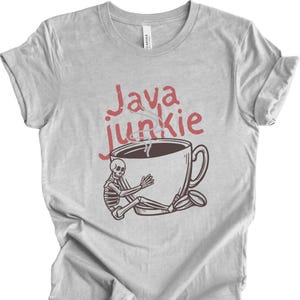 May include: Light gray t-shirt with a graphic of a skeleton embracing a coffee cup. The words "Java Junkie" are written above the cup in red. A coffee bean is next to the cup.