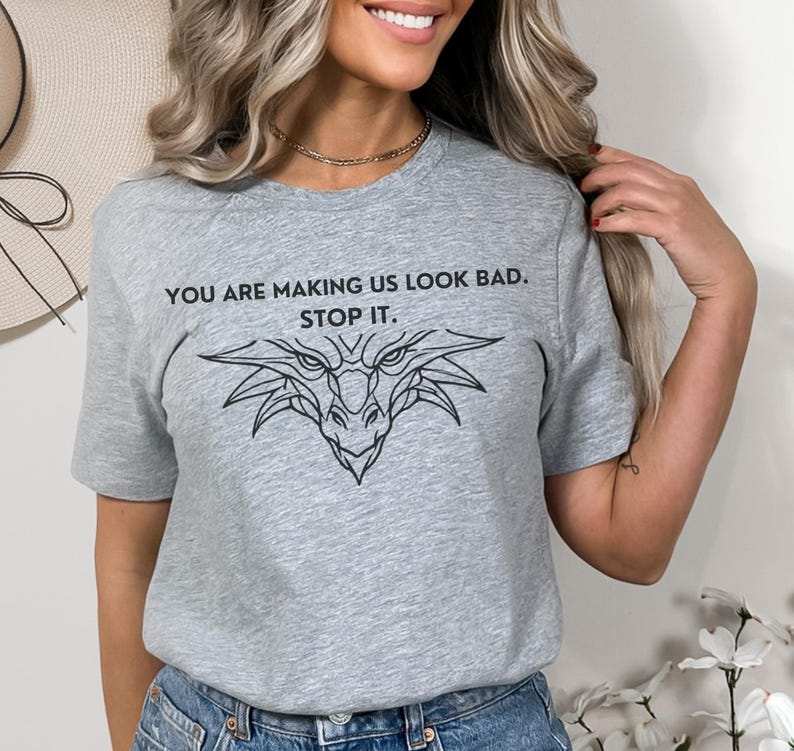 May include: Gray t-shirt with a black dragon graphic and the text "You are making us look bad. Stop it."