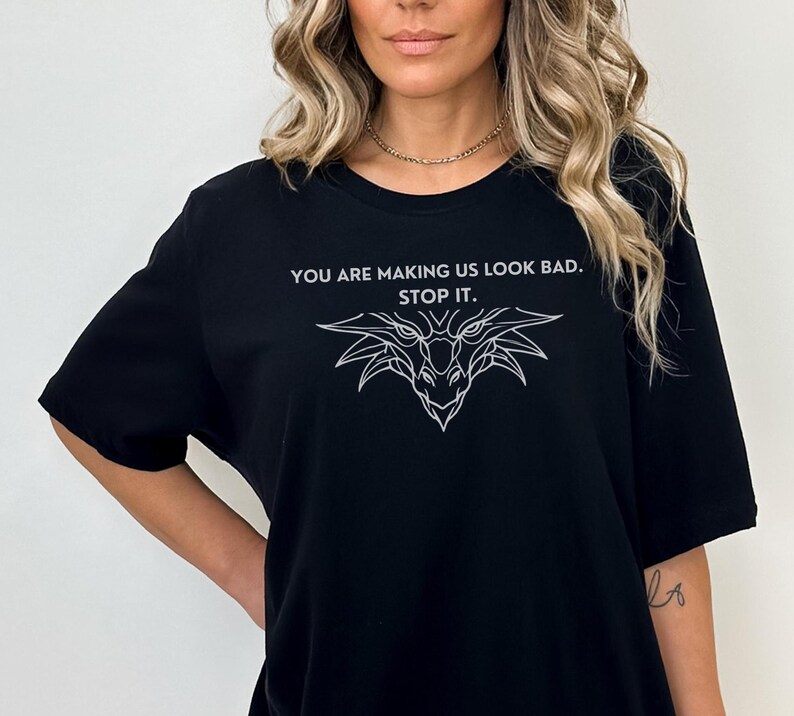May include: Black t-shirt with a white graphic of a dragon's head and the text "You are making us look bad. Stop it."