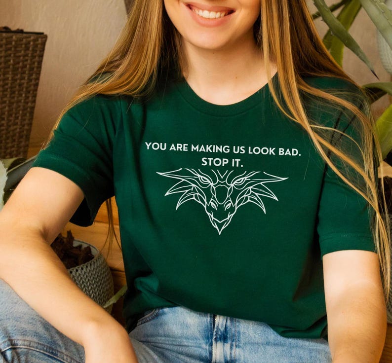 May include: A green t-shirt with a white dragon graphic and the text "You are making us look bad. Stop it."