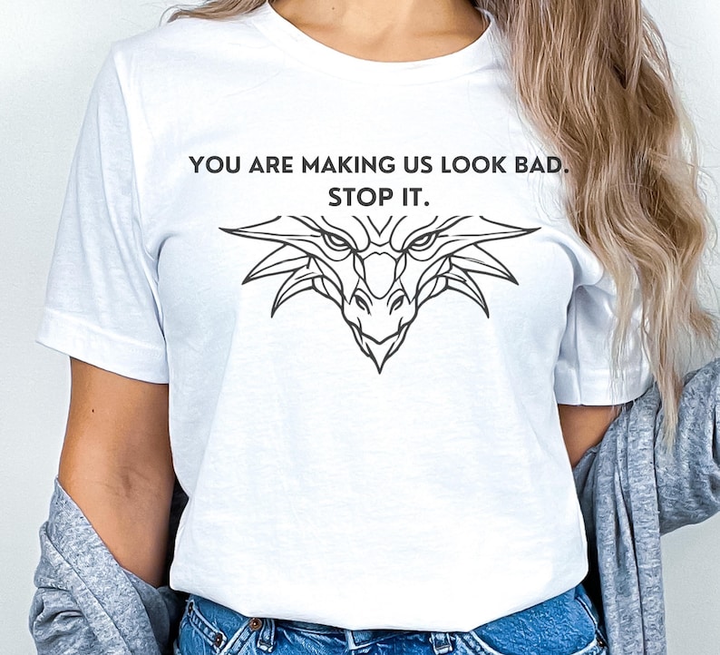 May include: White t-shirt with a black dragon graphic and the text "You are making us look bad. Stop it."