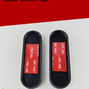 May include: Two black oval-shaped mounts with textured interiors, each featuring a rectangular red 3M VHB double-sided adhesive strip centered on the base. The text Affixing - Double Sided 3M tape is visible at the top, with Silver Harmony Studios LLC below.