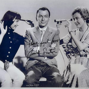 Peut inclure: Photographie en noir et blanc de Frank Sinatra avec deux femmes, toutes tenant de petits télescopes. Sinatra porte un costume, et l'image est signée "Peace and love, Frank Sinatra."