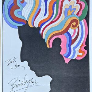 May include: A black and white silhouette of a person with colourful, abstract hair. The image is signed "Best wishes, Bob Dylan" and includes the word "DYLAN" in large, orange letters.
