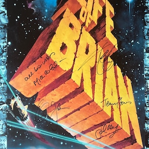May include: A movie poster for the film "Monty Python's Life of Brian" featuring a large, yellow, 3D-style title with a spaceship flying in the background. The poster is signed by the members of Monty Python.