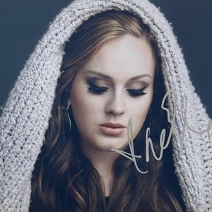 May include: A portrait of a woman with long, wavy brown hair, wearing a light gray, hooded knit shawl. Her eyes are closed, and she has dark eye makeup. The image has a signature in the lower right corner.