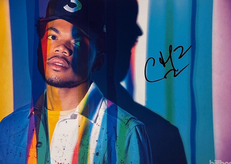 May include: Portrait of a person wearing a black baseball cap with a white and green logo. The person is wearing a denim jacket over a yellow shirt. The background features colorful vertical stripes and a signature.