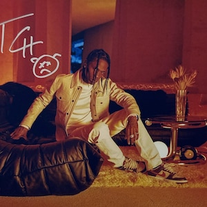 Puede incluir: Una persona con una chaqueta color crema y pantalones blancos está sentada en un sofá de cuero negro. La imagen tiene un tono cálido, marrón rojizo. El texto "TCH" y una cara triste están dibujados en la pared. La persona lleva zapatillas marrones y blancas.