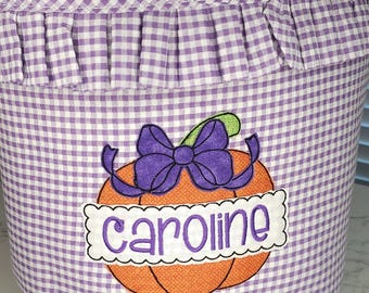 May include: A purple and white gingham fabric basket with a handle. The basket features a pumpkin applique with a purple bow and the name "Caroline". The text "Sew Blessed Stitches" is on a wooden tag.