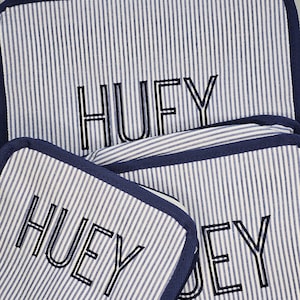 May include: Three matching rectangular and square fabric items with a blue and white striped pattern. The word "HUEY" is embroidered in black on each item. The edges are trimmed with a solid navy blue fabric.