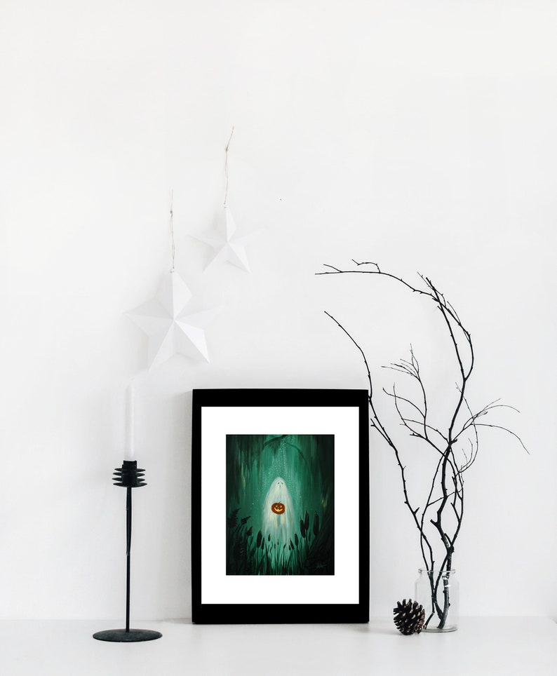 May include: A framed illustration of a ghost holding a jack-o'-lantern in a dark green forest setting. The frame is black and the illustration is surrounded by a white mat.