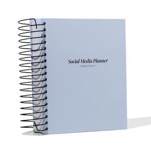 May include: A pale blue spiral-bound planner featuring the text "Social Media Planner" and "Stillness Planners" in black. It has a black metal spiral binding along the left edge.