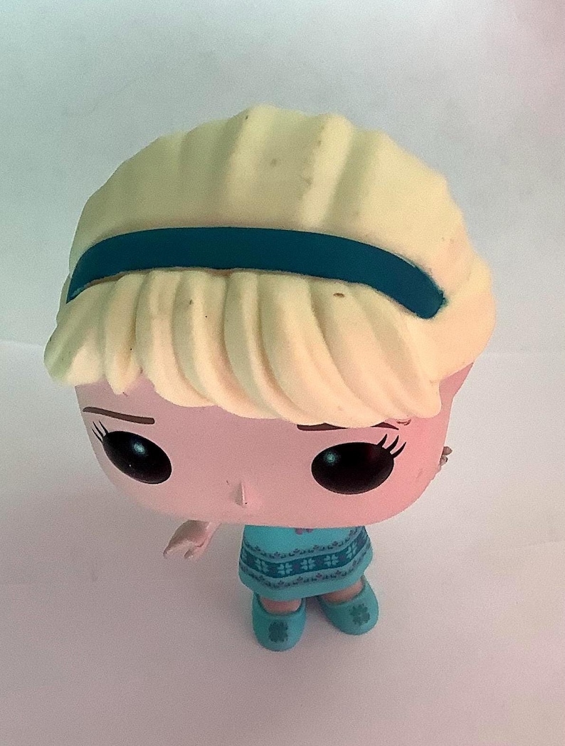 May include: A Funko Pop figure of a character with a light blonde hairstyle, a teal headband, and a teal dress. The figure has large black eyes and is wearing teal shoes. The figure is a collectible item.