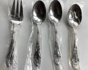 May include: Four silver-toned utensils, including a fork and three spoons, are individually packaged in clear plastic bags. The spoons have ornate designs and one has a slotted design.