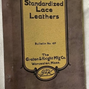 Könnte beinhalten: Ein antikes Büchlein mit dem Titel "Standardized Lace Leathers". Das Cover ist ein verblasstes Braun mit einem gelb-schwarz umrandeten Abschnitt mit dem Titel, Firmennamen und "Bulletin Nr. 107". Die Firma ist "Graton & Knight Mfg Co." aus Worcester, Mass.