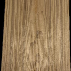 May include: Two pieces of light brown wood with vertical grain patterns. The wood has a natural, warm tone with darker streaks running throughout. The grain is straight and consistent, creating a visually appealing texture. The wood appears to be unfinished.