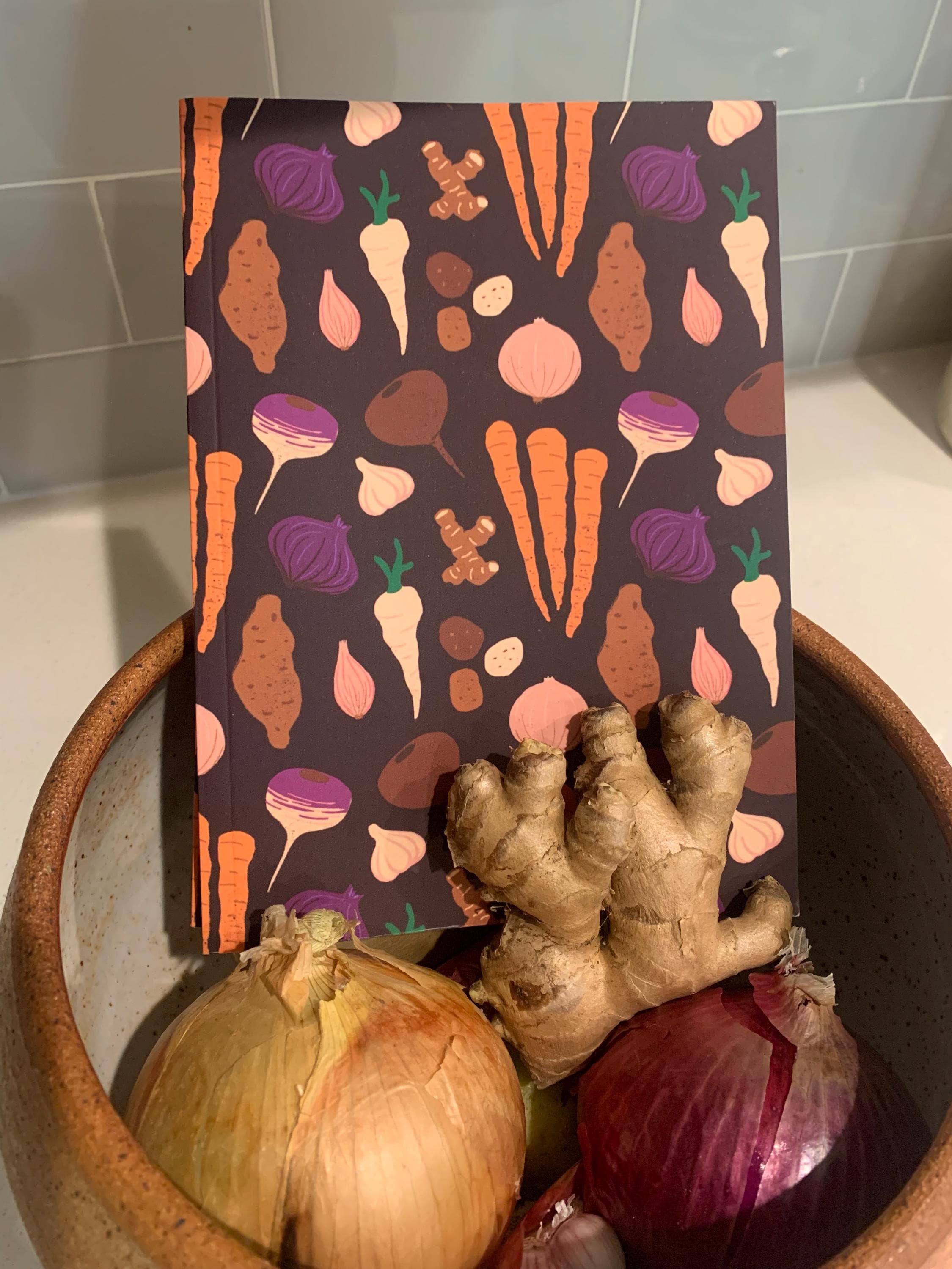 notebook sitting among its inspiration -- a bunch of root vegetables