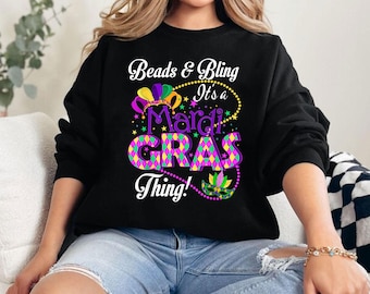 May include: Black sweatshirt with a colorful Mardi Gras design that says "Beads & Bling It's a Mardi Gras Thing!"