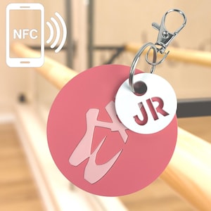 May include: Pink round keyring with a ballet shoe design and a white circle with the initials "JR" on it. The keyring has a silver clip.
