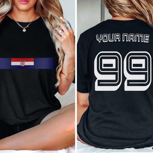 May include: A black short-sleeved t-shirt featuring a horizontal stripe with the Croatian flag on the front. The back of the shirt displays the text YOUR NAME above the large white number 99 in a bold, block-style font with a black outline.