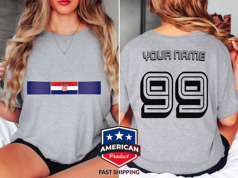 May include: A heather gray t-shirt featuring a horizontal graphic on the front with the Croatian flag centered between two dark blue bars. The back of the shirt displays the text YOUR NAME in black letters above the large black number 99.