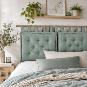 May include: A sage green tufted headboard featuring a series of fabric loops suspended from a horizontal wooden rod. The headboard is composed of two rectangular, button-tufted cushions, complemented by a matching sage green rectangular pillow.
