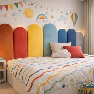 Puede incluir: Un dormitorio infantil colorido con una cama con temática de arcoíris. La cama tiene un edredón a rayas y una cabecera con paneles arqueados en varios colores. Las decoraciones de la pared incluyen un sol, nubes y un arcoíris. Una mesita de noche con una lámpara y juguetes está a la izquierda.