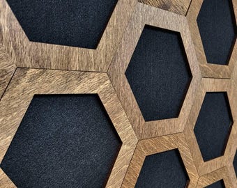 May include: Wooden wall art featuring a honeycomb design. The artwork has a natural wood finish with dark gray hexagonal inserts. The geometric pattern creates a modern and textured aesthetic, suitable for home decor.