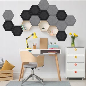 Könnte beinhalten: Ein weißer Schreibtisch mit einem Holzstuhl und eine weiße Kommode mit gelben und orangen Schubladenknöpfen. Die Wand hinter dem Schreibtisch hat eine wabenförmige schallabsorbierende Wandverkleidung aus grauem und schwarzem Stoff.