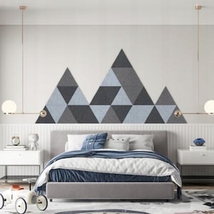 Könnte beinhalten: Ein Schlafzimmer mit einem grauen Bettgestell und weißen Bettwäsche. Das Kopfteil ist mit einem geometrischen Muster aus grauen und blauen Dreiecken verziert. Es gibt zwei weiße Nachttische mit Lampen auf beiden Seiten des Bettes.