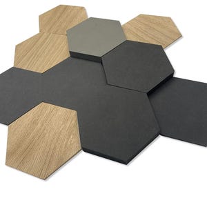 May include: A collection of hexagonal tiles in different colours and textures. The tiles feature shades of grey, black, and wood grain, arranged in a cluster. The arrangement suggests a design element for interior decor or a similar application.