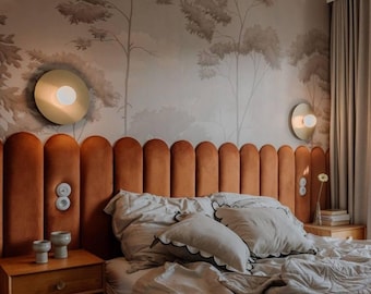 May include: A tall, vertical channel-tufted headboard upholstered in burnt orange velvet, featuring integrated circular wall sconces with white glass globes and a light gray bedding set with scalloped edges on a wooden bed frame.