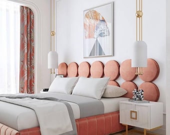 May include: A bedroom set featuring a bed with a coral-colored, circular-tufted headboard and a matching upholstered base. The bed is dressed in white and gray linens. Two white nightstands with gold accents and hanging pendant lights are included.