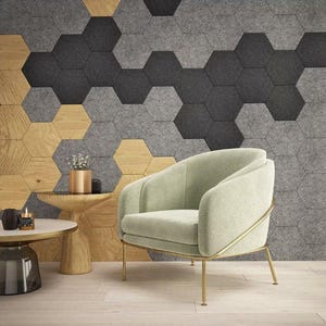 Könnte beinhalten: Ein hellgrüner Sessel mit goldenem Metallgestell steht vor einer Wand, die mit grauen und braunen sechseckigen Fliesen bedeckt ist. Der Sessel hat eine geschwungene Rückenlehne und eine bequem aussehende Sitzfläche.