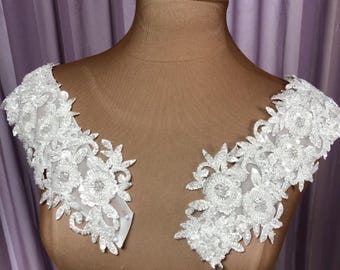 May include: White lace applique with sequins, perfect for adding a touch of elegance to a wedding dress or other special occasion garment.