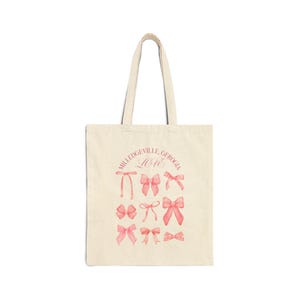 May include: A white tote bag with pink bows and the text "Milledgeville, Georgia Love" printed on the front.