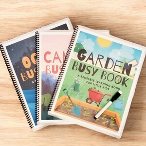 以下が含まれることがあります： 小さな子供のための、再利用可能な学習ブック3冊。ブックのタイトルは「Ocean Busy Book」、「Camp Busy Book」、「Garden Busy Book」。各ブックは表紙にカラフルなイラストと黒いマーカーが付いています。