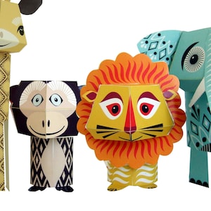 Puede incluir: Cuatro figuras de animales de papel: una jirafa, un mono, un león y un elefante. La jirafa es amarilla con manchas marrones, el mono es blanco y negro, el león es naranja y amarillo, y el elefante es azul claro con detalles blancos y negros.